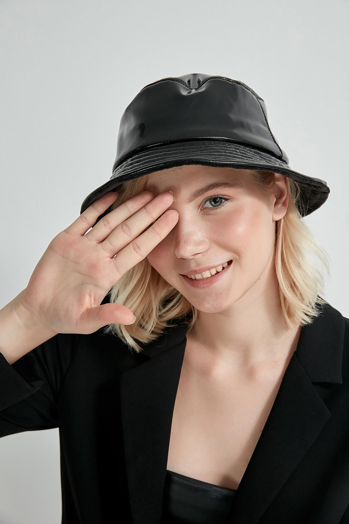 A model wears NSV11144 - Patent Leather Bucket Hat - Black, wholesale Hat of Nesvay to display at Lonca